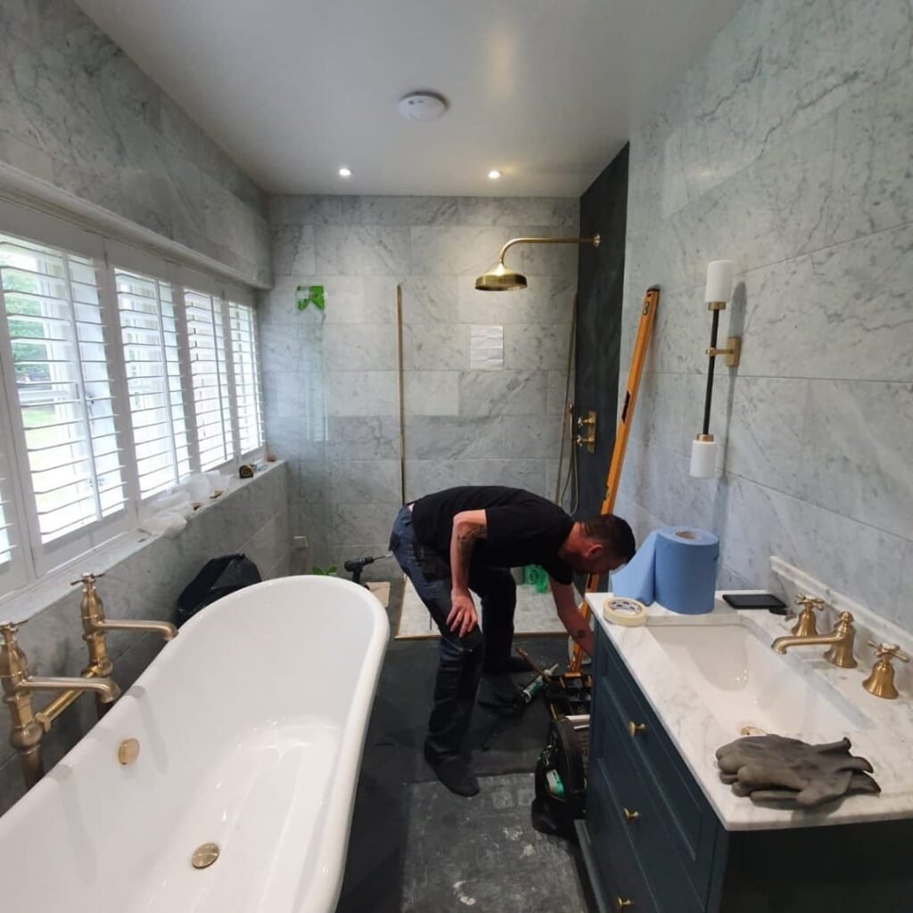 Glass Fit fitter bending down in a bathroom working